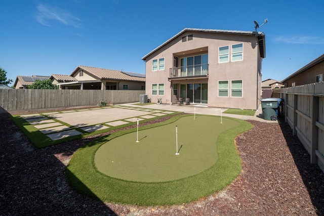 5615 N Lucy Ruiz Ave, Fresno, CA 93723 - back of house featuring a putting green, a balcony, a patio, stucco siding, and a fenced backyard