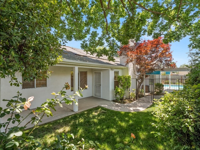 6185 N Milburn Ave, Fresno, CA 93722 - back of property featuring stucco siding, a patio, a shingled roof, and roof mounted solar panels