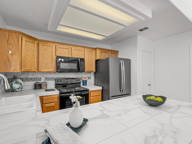 6185 N Milburn Ave, Fresno, CA 93722 - kitchen with black appliances, a sink, backsplash, and light stone countertops