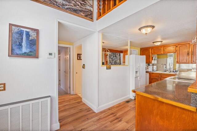 37731 Shoreline Dr, Bass Lake, CA 93604 - kitchen with white refrigerator with ice dispenser, light wood finished floors, brown cabinetry, a sink, and baseboards