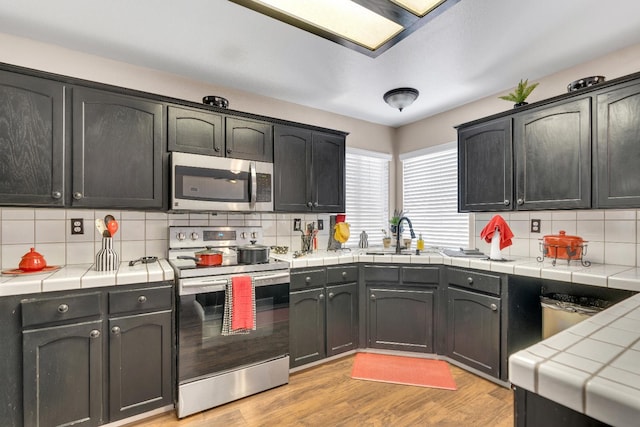 1775 E Cole Ave, Fresno, CA 93720 - kitchen with stainless steel appliances, tile countertops, a sink, and decorative backsplash