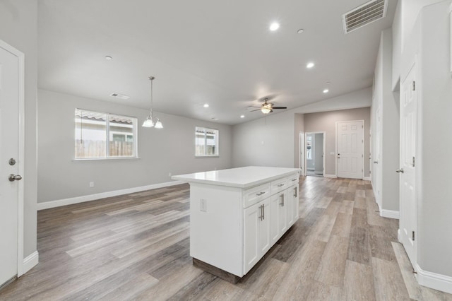 1061 Adell St, Madera, CA 93638 - kitchen with open floor plan, a ceiling fan, a kitchen island, white cabinetry, and light wood finished floors