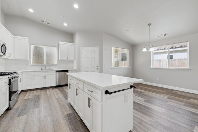 1061 Adell St, Madera, CA 93638 - kitchen with vaulted ceiling, appliances with stainless steel finishes, a sink, a chandelier, and backsplash
