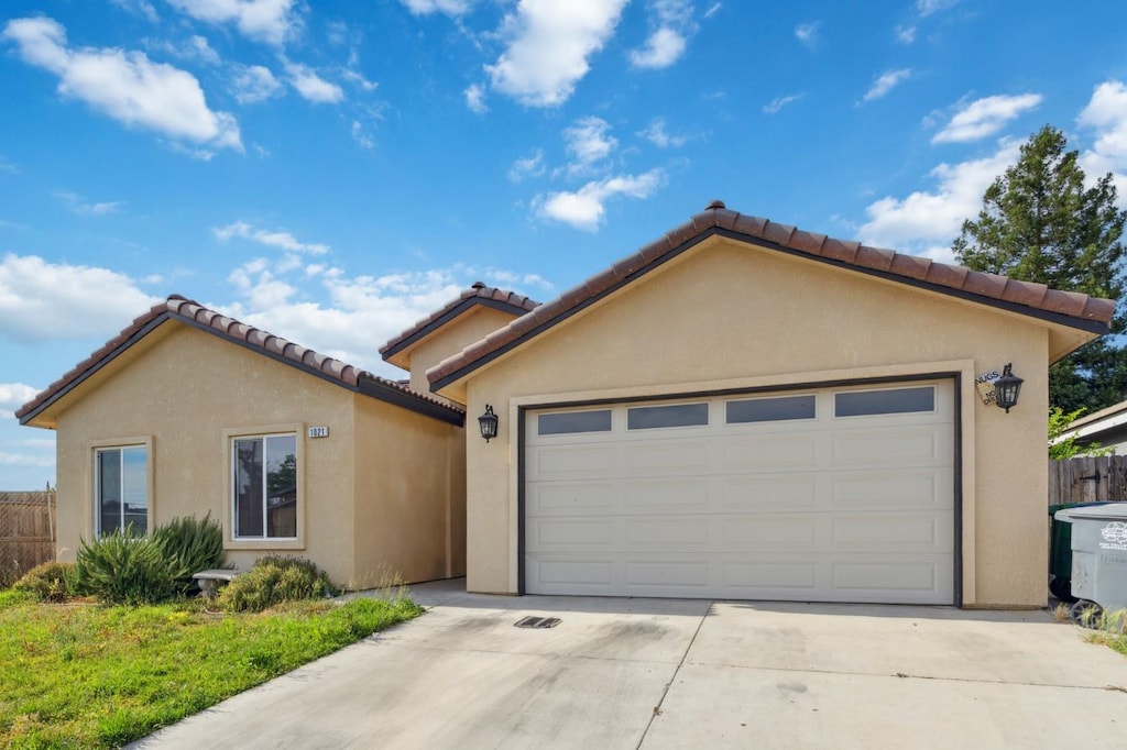 1021 Adell St, Madera, CA 93638 - mediterranean / spanish house with stucco siding, driveway, an attached garage, and a tile roof