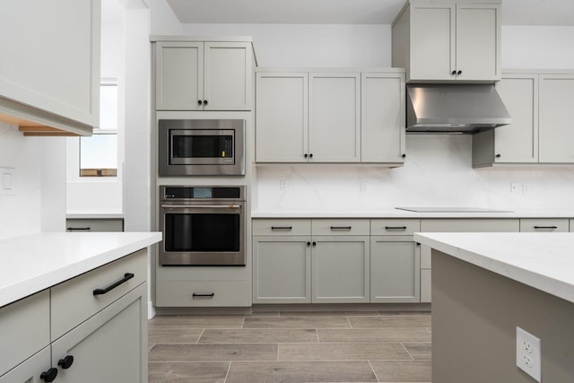 8152 Creek Vw, Friant, CA 93626 - kitchen featuring appliances with stainless steel finishes, wall chimney exhaust hood, light countertops, wood tiled floors, and decorative backsplash