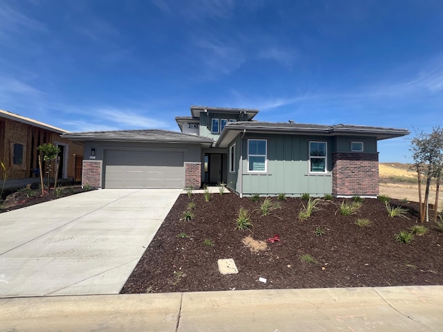 8131 Creek Vw, Friant, CA 93626 - prairie-style house with board and batten siding, an attached garage, concrete driveway, and brick siding