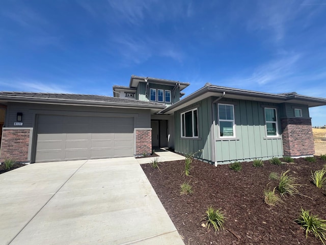 8131 Creek Vw, Friant, CA 93626 - prairie-style home with board and batten siding, driveway, brick siding, and an attached garage