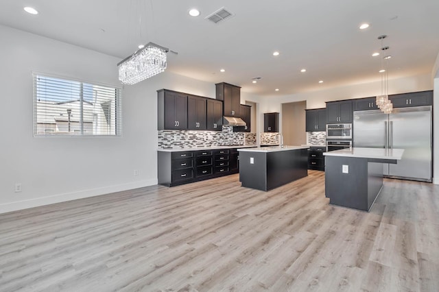 1734 Lester Ave, Clovis, CA 93619 - kitchen with stainless steel built in refrigerator, a kitchen island with sink, under cabinet range hood, light countertops, and tasteful backsplash