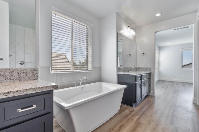 1734 Lester Ave, Clovis, CA 93619 - full bath featuring wood finished floors, a freestanding tub, vanity, backsplash, and recessed lighting