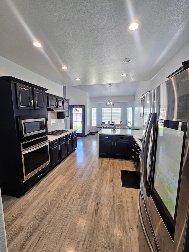5453 N San Clemente Ave, Fresno, CA 93723 - kitchen featuring stainless steel appliances, dark cabinets, a textured ceiling, light wood-style floors, and light countertops