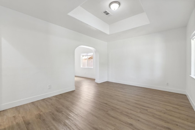 630 N Roosevelt Ave, Fresno, CA 93728 - unfurnished room featuring a tray ceiling, wood finished floors, arched walkways, and baseboards