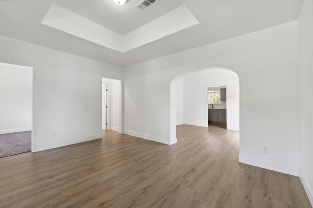 630 N Roosevelt Ave, Fresno, CA 93728 - spare room featuring arched walkways, a raised ceiling, baseboards, and wood finished floors