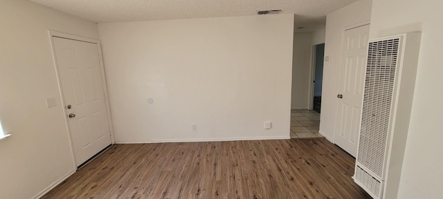 2025 E White Ave, Fresno, CA 93701 - unfurnished room with a heating unit, wood finished floors, a textured ceiling, and baseboards