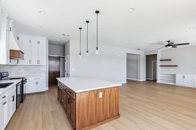 8385 Lake Shore Dr, Chowchilla, CA 93610 - kitchen with black / electric stove, a kitchen island, a ceiling fan, light wood-style floors, and decorative backsplash