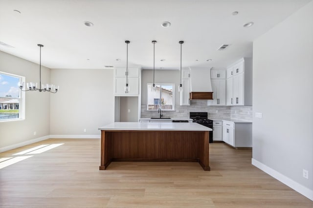 8385 Lake Shore Dr, Chowchilla, CA 93610 - kitchen featuring black range with gas cooktop, a sink, premium range hood, backsplash, and white cabinetry