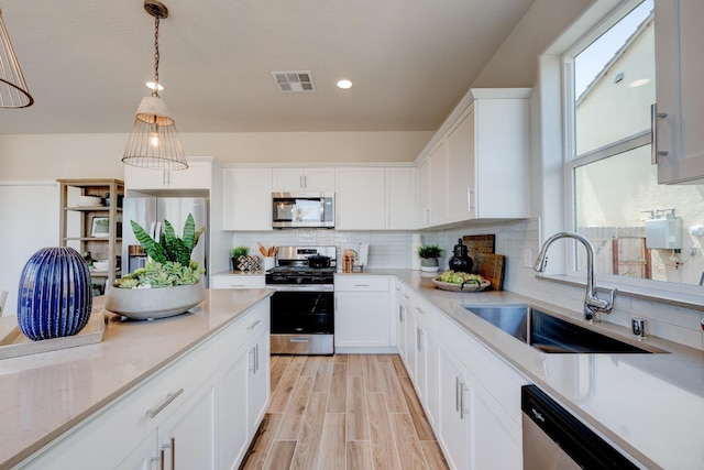 1151 Maclure Ave W, Madera, CA 93636 - kitchen with stainless steel appliances, a sink, decorative backsplash, white cabinetry, and recessed lighting