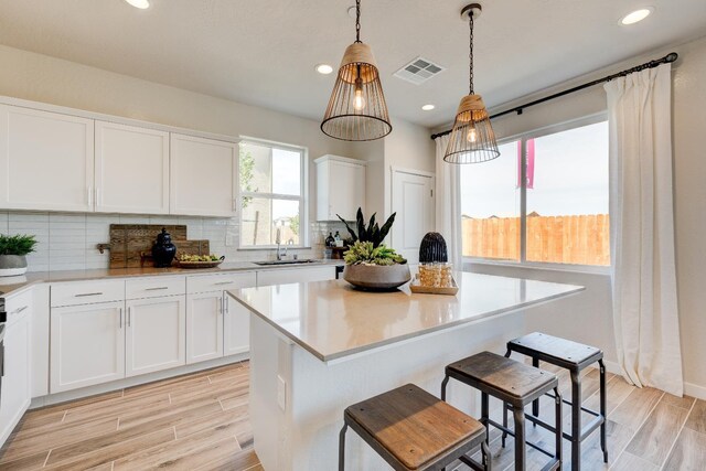1151 Maclure Ave W, Madera, CA 93636 - kitchen featuring backsplash, light wood-style flooring, white cabinets, and recessed lighting