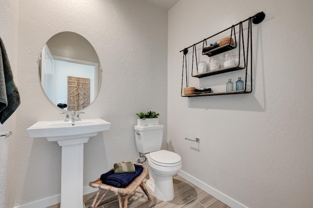 1151 Maclure Ave W, Madera, CA 93636 - bathroom with wood finished floors, toilet, baseboards, and a textured wall