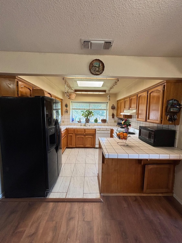 32633 Rd 222, North Fork, CA 93643 - kitchen with black appliances, a peninsula, tile countertops, brown cabinets, and decorative backsplash
