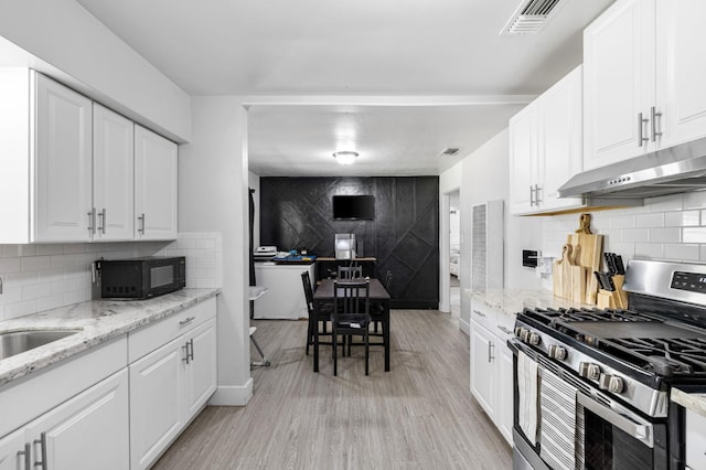958 E Cornell Ave, Fresno, CA 93704 - kitchen featuring gas stove, black microwave, under cabinet range hood, tasteful backsplash, and white cabinetry