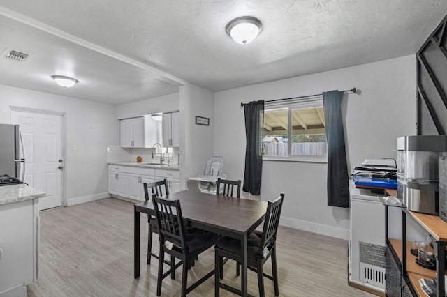 958 E Cornell Ave, Fresno, CA 93704 - dining area featuring light wood-style flooring, baseboards, and a textured ceiling