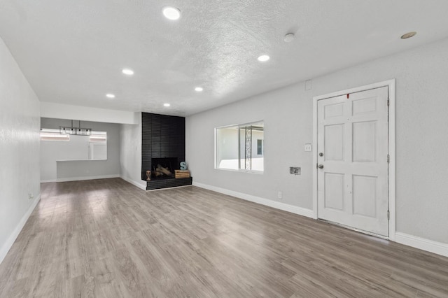 4641 E Weldon Ave, Fresno, CA 93703 - unfurnished living room featuring wood finished floors, recessed lighting, a fireplace, baseboards, and a textured ceiling