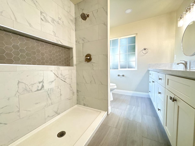 4221 E Grant Ave, Fresno, CA 93702 - full bathroom with toilet, tiled shower, vanity, baseboards, and wood finished floors