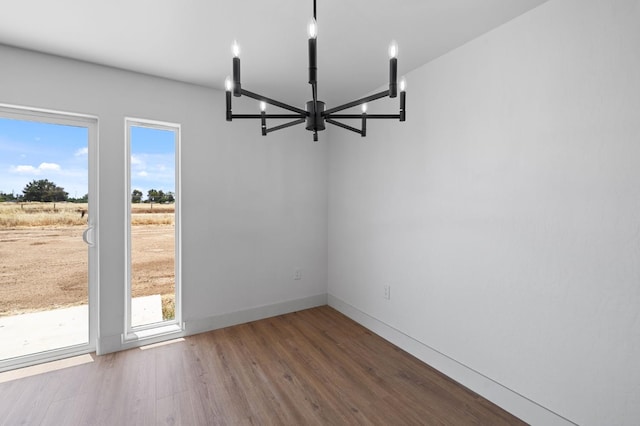25900 Tanforan Dr, Madera, CA 93638 - unfurnished dining area with a chandelier, wood finished floors, and baseboards