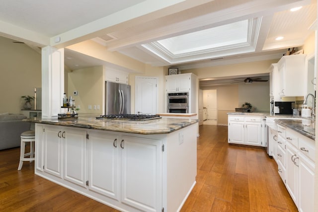 499 E Braddock Dr, Fresno, CA 93720 - kitchen with appliances with stainless steel finishes, a peninsula, stone countertops, white cabinets, and hardwood / wood-style flooring