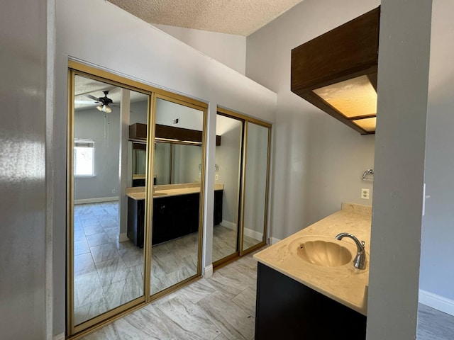 2761 N Selland, Fresno, CA 93722 - bathroom featuring vanity, a textured ceiling, ceiling fan, baseboards, and marble finish flooring