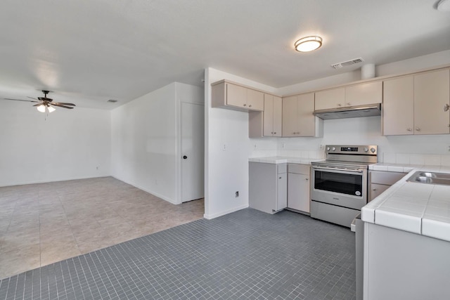 829 W Woodward Ave, Fresno, CA 93706 - kitchen featuring stainless steel range with electric stovetop, tile countertops, under cabinet range hood, and cream cabinetry