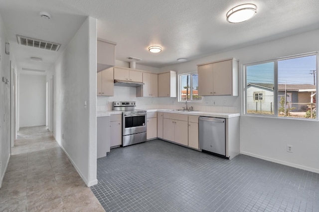 829 W Woodward Ave, Fresno, CA 93706 - kitchen featuring appliances with stainless steel finishes, light countertops, baseboards, cream cabinets, and a sink