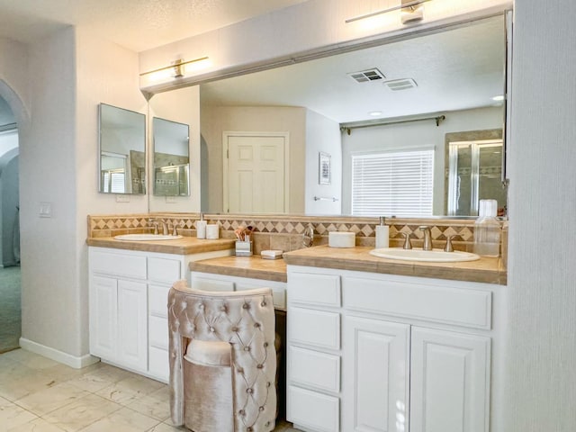 9130 Hunters Creek Way, Chowchilla, CA 93610 - full bathroom featuring tasteful backsplash, double vanity, a stall shower, and marble look tile flooring