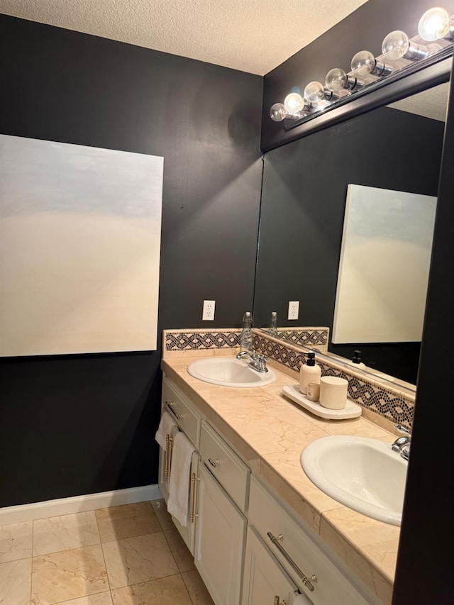 9130 Hunters Creek Way, Chowchilla, CA 93610 - bathroom with double vanity, a textured ceiling, marble finish flooring, and baseboards