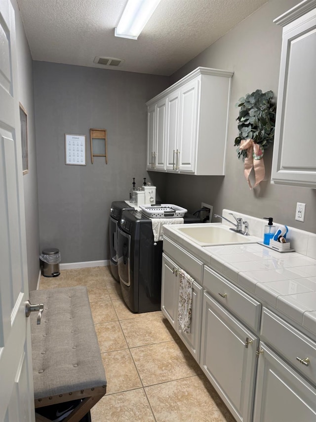 9130 Hunters Creek Way, Chowchilla, CA 93610 - laundry area with cabinet space, washing machine and clothes dryer, a textured ceiling, light tile patterned flooring, and baseboards