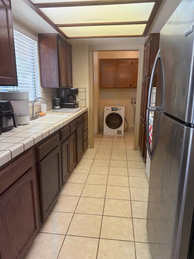 4352 W Los Altos, Fresno, CA 93722 - kitchen with freestanding refrigerator, washer / clothes dryer, light tile patterned floors, tile counters, and dark brown cabinets