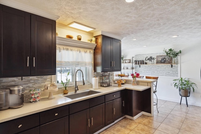 5554 E Montecito Ave, Fresno, CA 93727 - kitchen featuring a sink, backsplash, light countertops, a textured ceiling, and light tile patterned floors