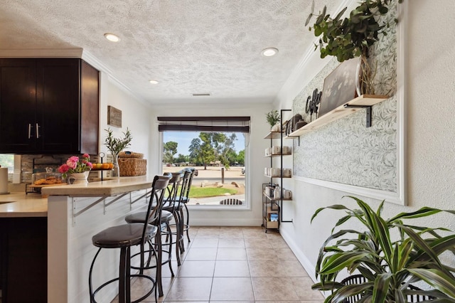 5554 E Montecito Ave, Fresno, CA 93727 - kitchen with a kitchen breakfast bar, a textured ceiling, light countertops, light tile patterned floors, and baseboards
