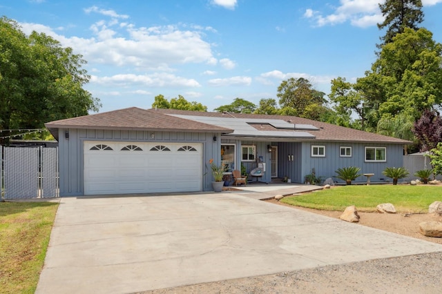 5554 E Montecito Ave, Fresno, CA 93727 - ranch-style home featuring concrete driveway, solar panels, a garage, a shingled roof, and board and batten siding