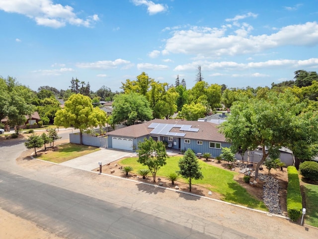 5554 E Montecito Ave, Fresno, CA 93727 - view of front facade featuring driveway, a garage, roof mounted solar panels, and a front lawn