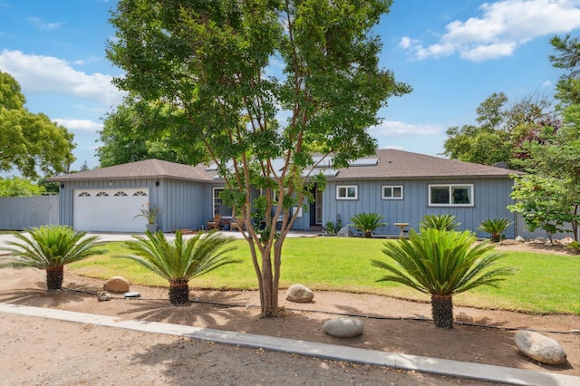 5554 E Montecito Ave, Fresno, CA 93727 - ranch-style home featuring board and batten siding, a front lawn, a garage, roof mounted solar panels, and roof with shingles