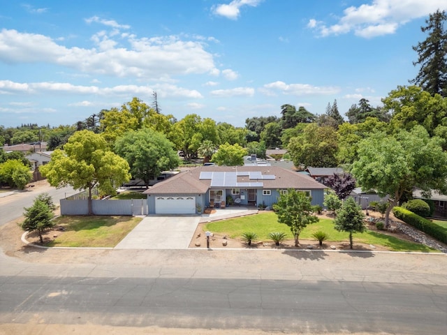 5554 E Montecito Ave, Fresno, CA 93727 - view of front facade with roof mounted solar panels, driveway, a garage, and view of scattered trees