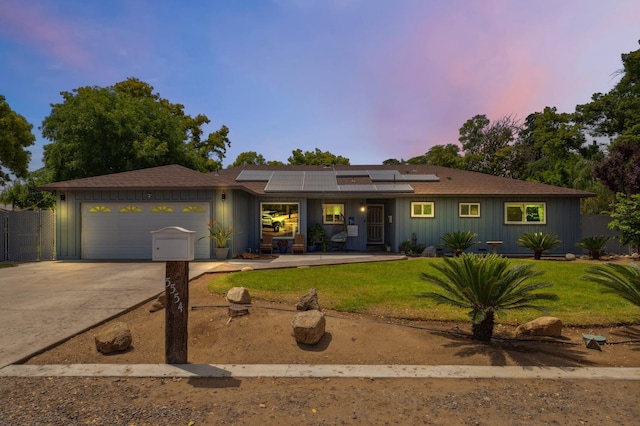 5554 E Montecito Ave, Fresno, CA 93727 - ranch-style home featuring an attached garage, driveway, roof mounted solar panels, covered porch, and board and batten siding