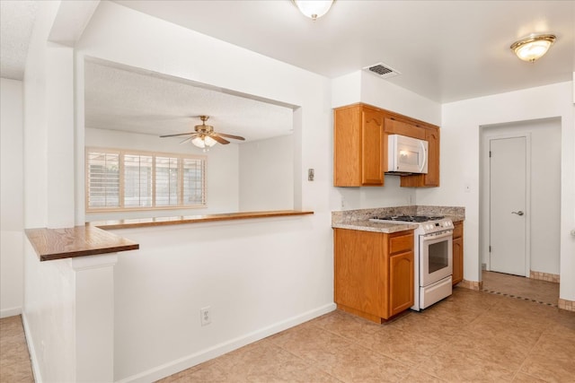 4705 N Holt Ave, Fresno, CA 93705 - kitchen with white appliances, baseboards, brown cabinetry, and ceiling fan