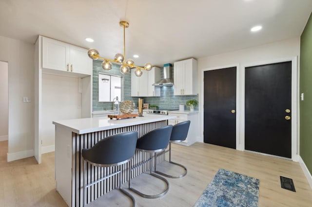 4489 N Chestnut Ave, Fresno, CA 93726 - kitchen with wall chimney range hood, white cabinetry, light countertops, light wood-type flooring, and recessed lighting