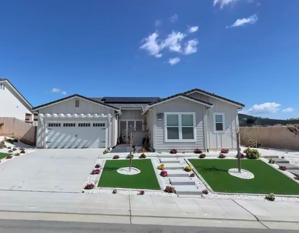20104 Marrone Way, Friant, CA 93626 - ranch-style home featuring board and batten siding, roof mounted solar panels, an attached garage, and concrete driveway