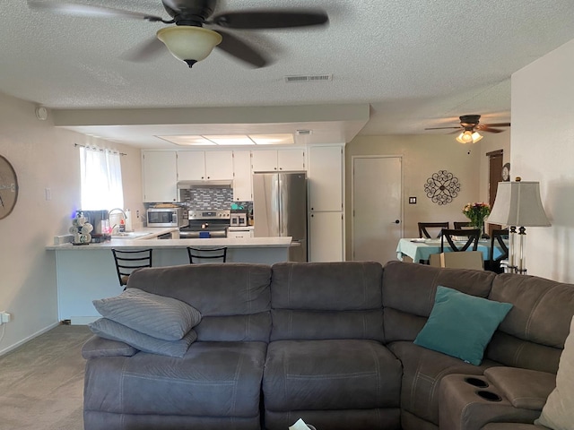 5815 E Lansing Way, Fresno, CA 93727 - living area with a ceiling fan, a textured ceiling, light carpet, and baseboards