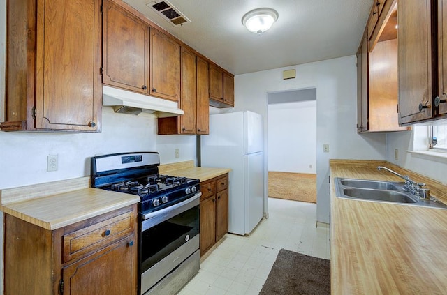 2100 E Linden Ave, Fresno, CA 93725 - kitchen with stainless steel gas range, under cabinet range hood, freestanding refrigerator, a sink, and light flooring