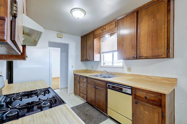 2100 E Linden Ave, Fresno, CA 93725 - kitchen featuring dishwashing machine, a sink, gas stove, freestanding refrigerator, and under cabinet range hood