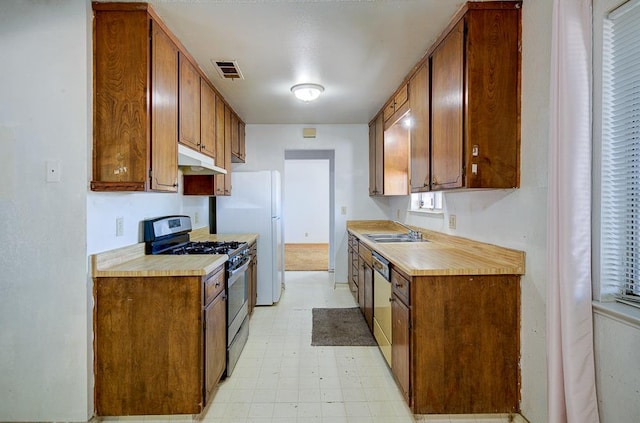 2100 E Linden Ave, Fresno, CA 93725 - kitchen with stainless steel gas range oven, a sink, dishwasher, light countertops, and light flooring